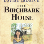 The cover of The Birchbark House has a girl standing outside a home in the woods